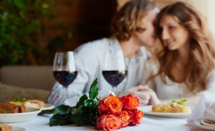 una pareja celebrando el día de los enamorados con cena y flores